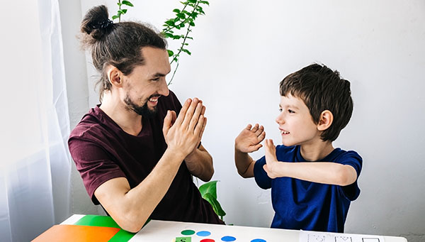 happy autism boy during therapy with school counselor, learning and having fun together